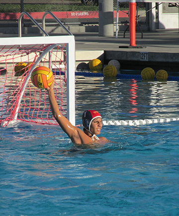 Goalie Andy from boys water polo searches for an opening to pass the ball to his teammate
