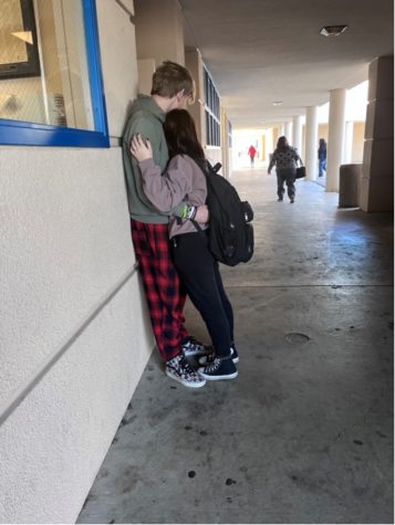 Two students hold each other against a wall in the hallway, on display for students and staff. 