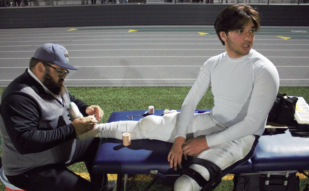 Senior Football player Caleb Cosme is taped by West High's physical therapist.