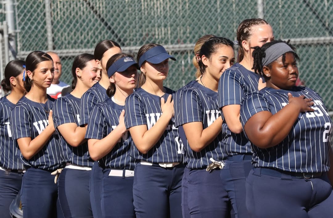 Varsity Girls Baseball saluting for the pledge of allegiance 